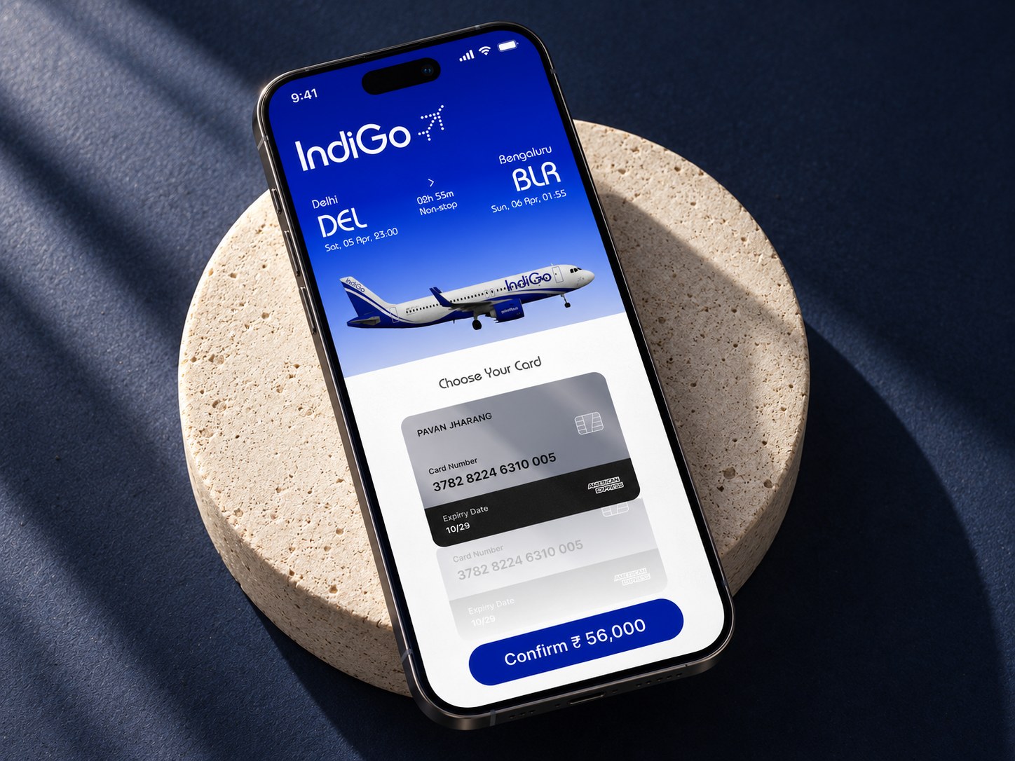 The IndiGo card-selection payment screen on a phone resting on a stone plinth.